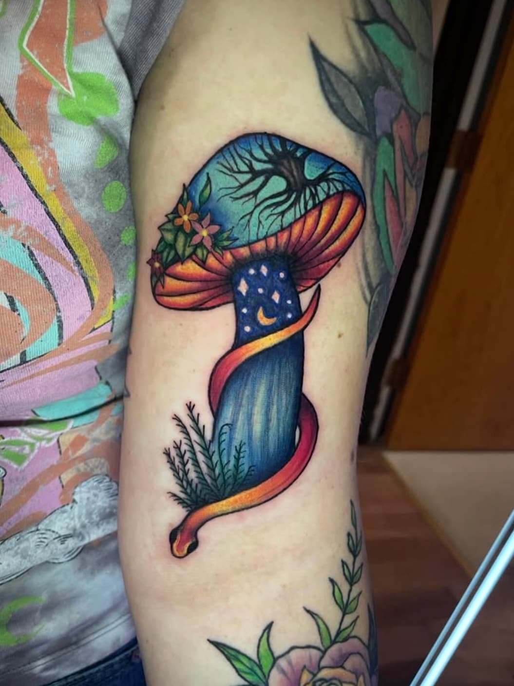 Vibrant mushroom tattoo with blue cap featuring celestial dots and orange gills on arm