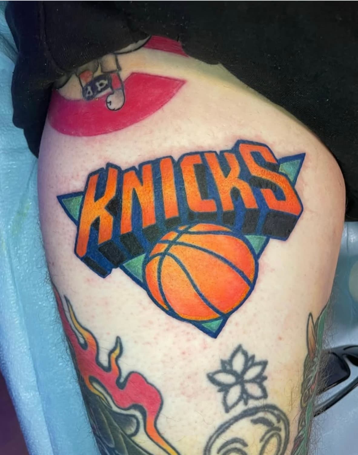 New York Knicks logo tattoo with basketball on person's thigh