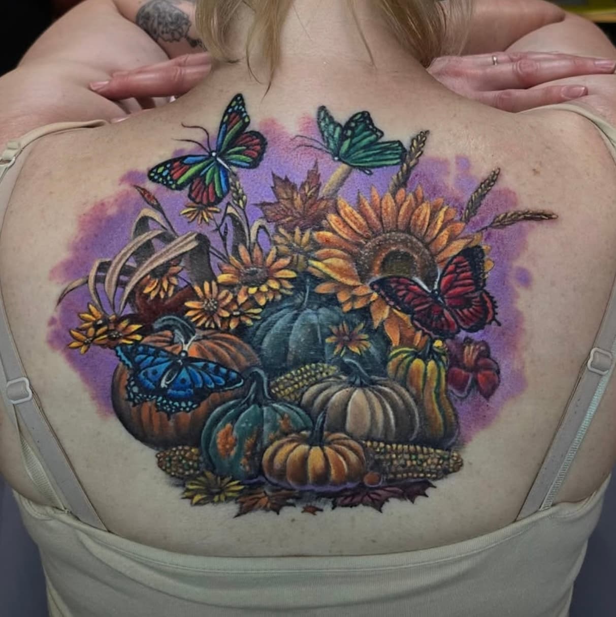 Colorful back tattoo featuring pumpkins, sunflowers, corn, and butterflies
