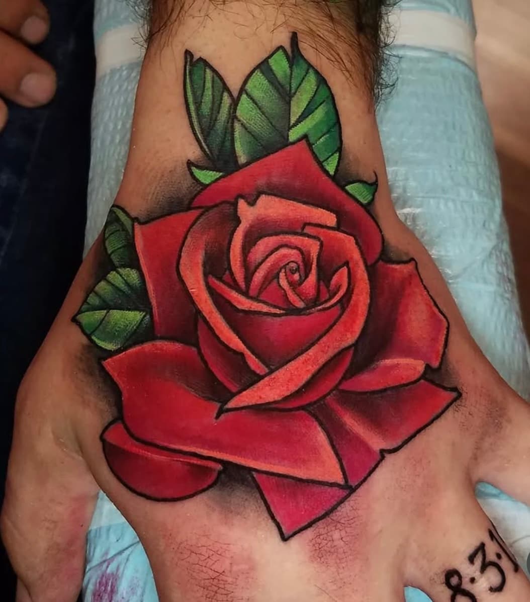 Red rose tattoo with green leaves on hand, bold traditional style