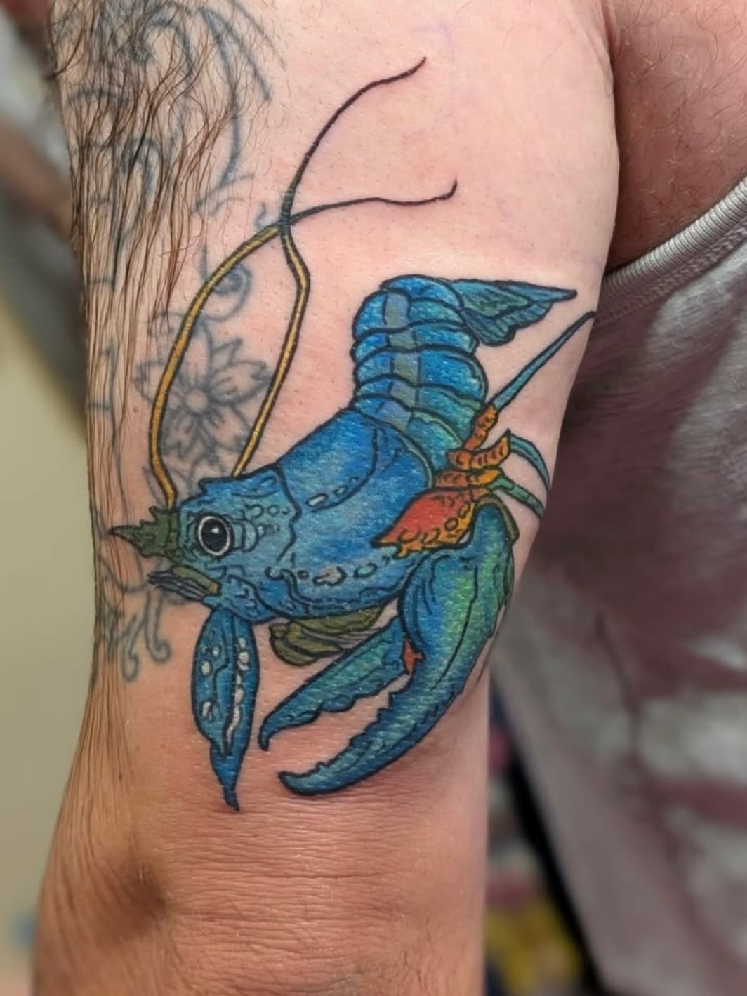 Blue and green dragon tattoo with orange accents on person's arm