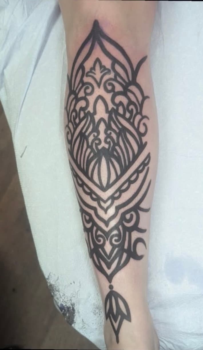 Black ornamental tattoo design with mandala elements on forearm