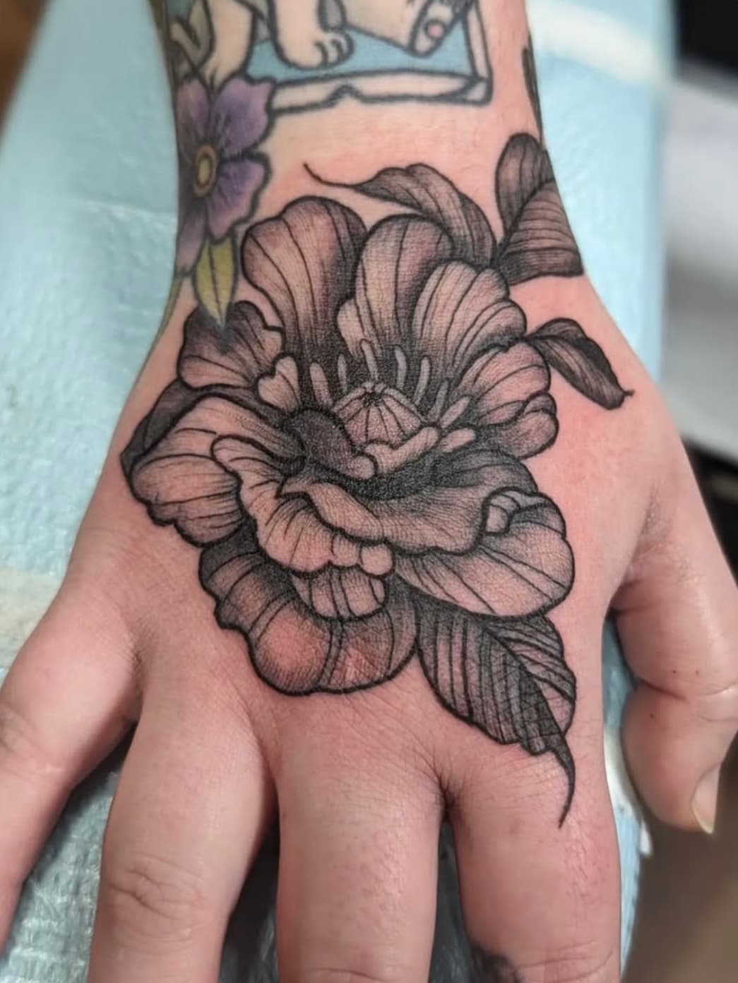 Black and gray peony flower tattoo on hand with detailed shading